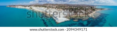 Aerial view of white rocky cliffs at Scala dei Turchi, Sicily, Italy, with turquoise clear water. Drone shot of the limestone rock formation and beach. Tourist attraction, travel holiday scenery.
