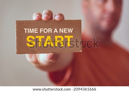 man holding a card board with the text time for a new start - business concept
