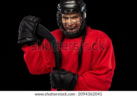 Ready to win. Motivated sportsman. Professional female hockey player in special protective helmet isolated over black background. Concept of sport, action, movement, health. Copy space for ad