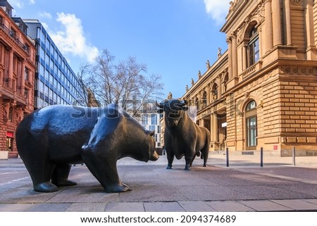 Place in front of the entrance to the Frankfurt Stock Exchange. Bull and bear as a symbol figure. Commercial buildings with a brown facade in the sunshine and blue sky with clouds in spring Royalty-Free Stock Photo #2094374689
