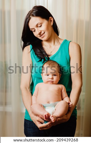 Young mother and her adorable baby boy. Beautiful mother holding baby boy, mom carry cute child adorable small son, happy family picture, mom and kid indoor brunette Arabic models, happiness concept