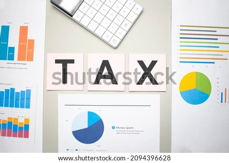 TAX concept. Text on the sheets of paper, charts and white calculator