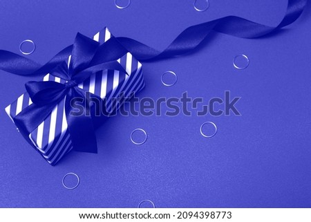 Striped gift box with ribbon and decorations. Tinting in the trendy color of the year, very peri, closeup.