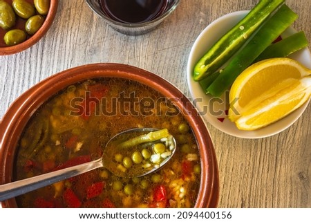 Typical Majorcan dish called Arroz Brut. Served with green pepper stripes and lemon wedges.  Some red wine and olives also accompanying the food. Royalty-Free Stock Photo #2094400156