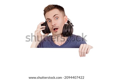 Young guy in studio wireless black headphones with surprise on his face listens to music on a white background with copy space. Call center operator, customer service agent portrait