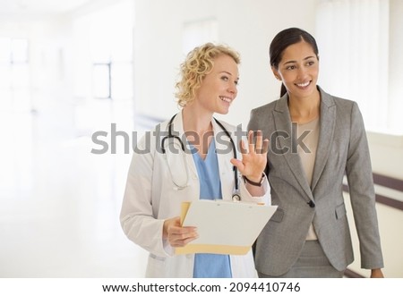 Doctor and businesswoman talking in hospital corridor Royalty-Free Stock Photo #2094410746