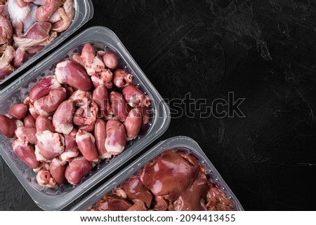 Chicken giblets pack set, on black dark stone table background, top view flat lay, with copy space for text