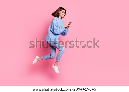 Full length body size view of attractive cheerful girl jumping using device chatting isolated over pink pastel color background