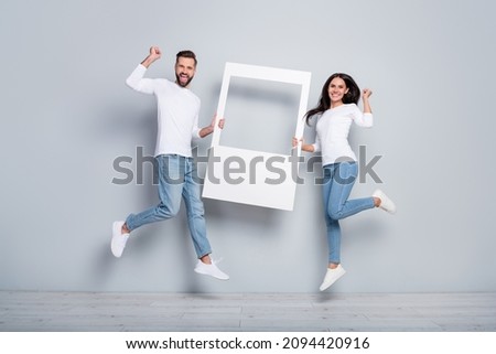 Full length body size view of trendy handsome beautiful friends friendship holding frame jumping isolated over grey pastel color background Royalty-Free Stock Photo #2094420916