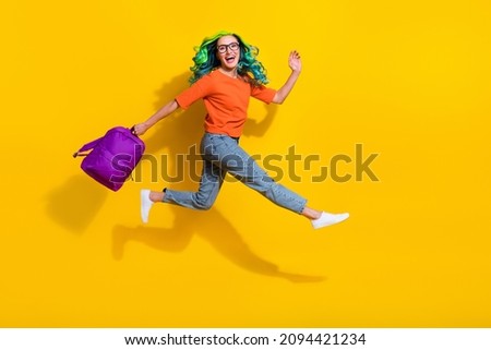 Photo of cute charming young vibrant woman wear orange t-shirt spectacles rucksack jumping running fast isolated yellow color background