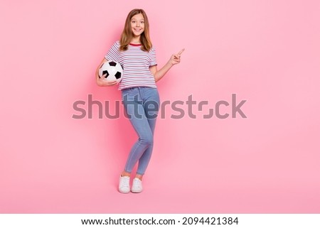 Full length photo of cool teenager blond girl hold ball index promo wear t-shirt jeans sneakers isolated on pink background