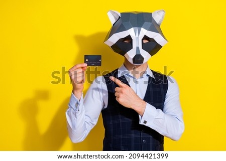 Photo of bizarre racoon mask guy hold point finger debit card choose advice party earnings isolated over shine yellow color background
