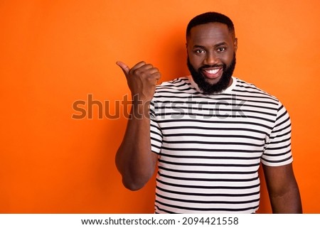 Photo of young african man indicate thumb empty space proposition ads select isolated over orange color background