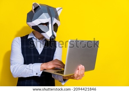 Photo of focused guy hold netbook write code wear raccoon mask vest isolated yellow color background