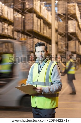 Worker writing on clipboard in warehouse