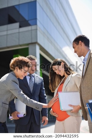 Businesswoman holding pregnant colleague belly