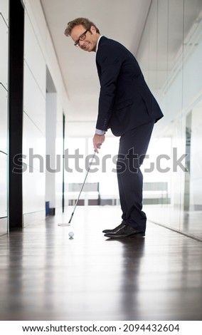 Businessman putting golf ball in office