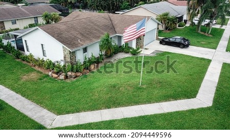 Aerial drone photo of South Florida residential house with American flag waving in front yard