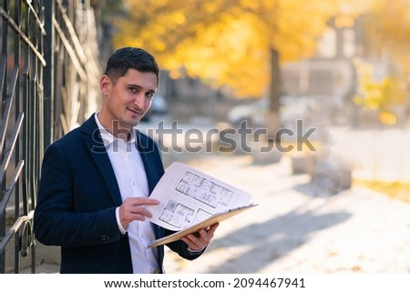 Pensive caucasian realtor in classic tie suit standing outside hold clipboard with papers and read document. Outside business portrait.