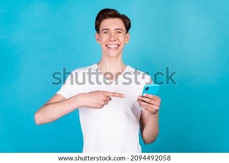 Photo of young guy indicate finger smartphone advertise recommend suggest isolated over blue color background