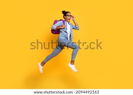 Full body profile side photo of young african girlhold bag run hurry on lesson look empty space jump isolated over yellow color background