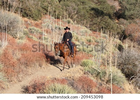 A cowboy on a high desert mountain trail.