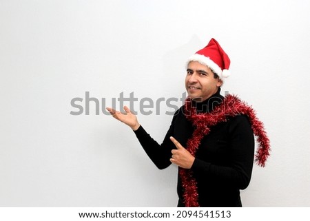 Dark Latino adult man with Christmas hat and garland excited and happy for the arrival of December and celebrating Christmas and New Years
