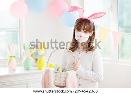 Easter egg hunt in covid 19 pandemic. Kid in bunny face mask. Coronavirus prevention during spring holiday. Child with eggs and rabbit ears. Safe Easter celebration for family with children.