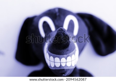 Cartoon dog stuffed soft toy close up with focused nose, big mouth and defocused face coloured very peri