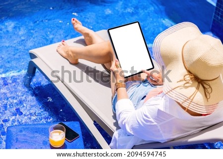 Woman using tablet computer by the pool, vertical screen mockup