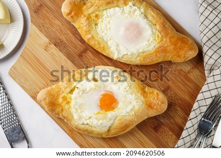 Traditional georgian dish of cheese-filled bread adjarian khachapuri with fried egg on a wooden board