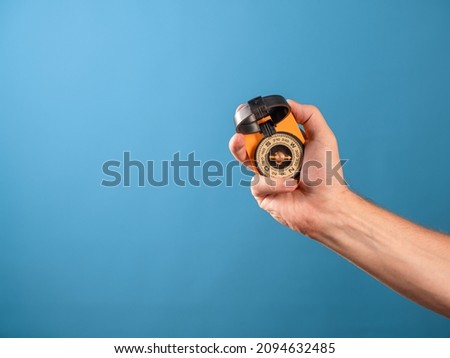 compass in the hand of a traveler, searching for yourself on the way, a concept. Magnetic compass in a man's hand, photo on a blue background