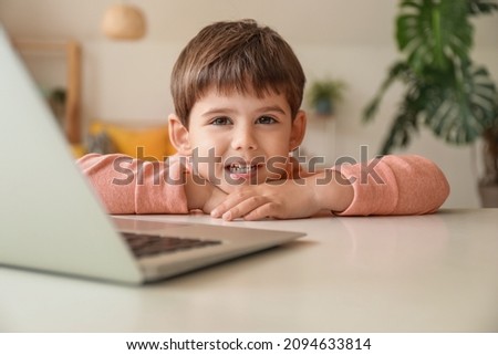 Little boy watching cartoons on laptop at table in living room