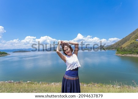 women take pictures with nature Behind it is a river, mountains, beautiful sky.