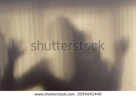 The ghost shadow. Shadow of horror man. Hands on the glass. Shadow of man. Dangerous man behind the frosted glass. Halloween background. Blur picture
