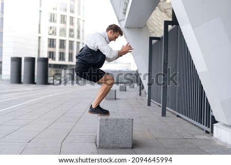 Do your best. Concept of dynamic exercise and cardio training in sport. Profile and full length view of young sportsman jumping up on box, warm up body, getting ready to run on the street Royalty-Free Stock Photo #2094645994