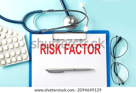 Paper with text RISK FACTOR on blue background with stethoscope and pills