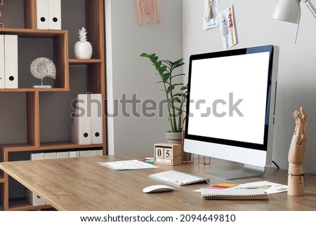 Modern workplace with computer near light wall