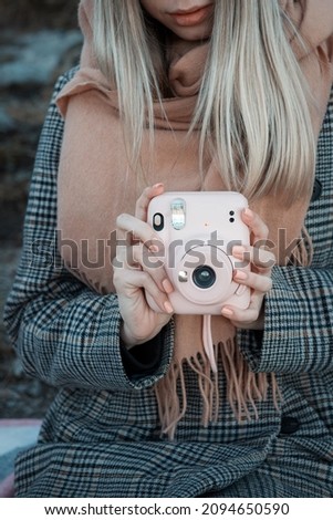 Close up of female hands with pink picture camera  Instax 