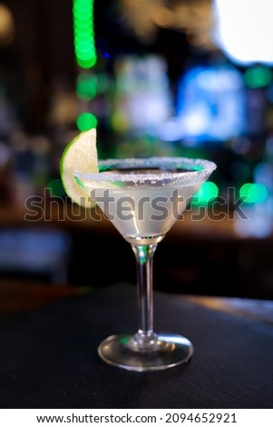 In a funnel-shaped glass with a long stem, the alcoholic cocktail is opaque, opaque, with a slice of lime on the sugared edge of the glass. 