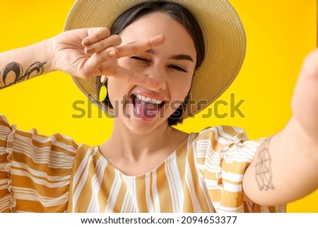 Beautiful woman showing victory gesture on yellow background