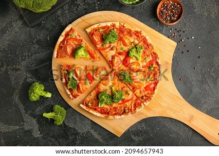 Board with tasty vegetarian pizza on dark background