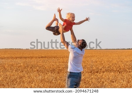 child is flying in fathers arms. Dad tosses son into the air. Father and son playing outdoors.
