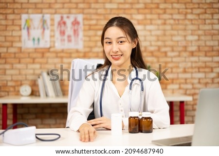 Portrait of beautiful female doctor of Asian ethnicity in white shirt with stethoscope, smiling and looking at the camera in hospital's clinic. Smiling asian woman physician in  home office.