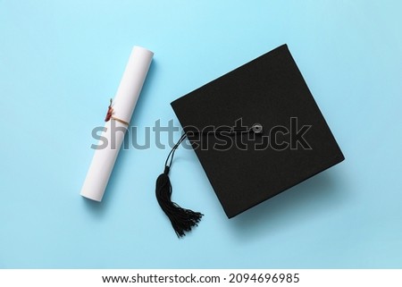 Graduation hat and diploma on color background Royalty-Free Stock Photo #2094696985