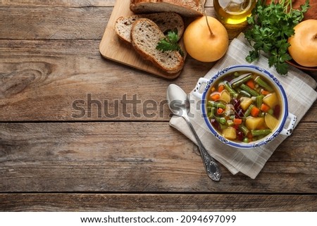 Bowl of tasty turnip soup with bread and ingredients on wooden table, flat lay. Space for text