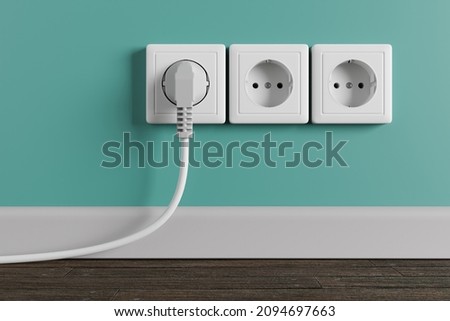 A white electrical outlet on the wall in the room. An electric plug with a cable in the socket. Royalty-Free Stock Photo #2094697663