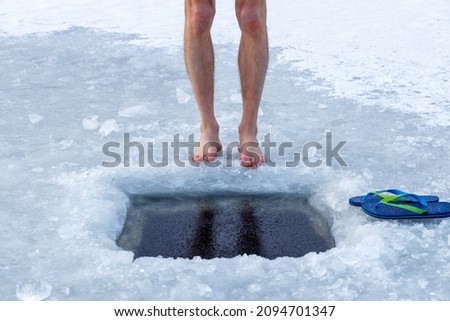 Man and ice hole. Legs and ice hole close-up. Health and cold water hardening concept. Royalty-Free Stock Photo #2094701347