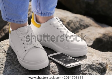 Legs of woman and damaged mobile phone on stone outdoors, closeup