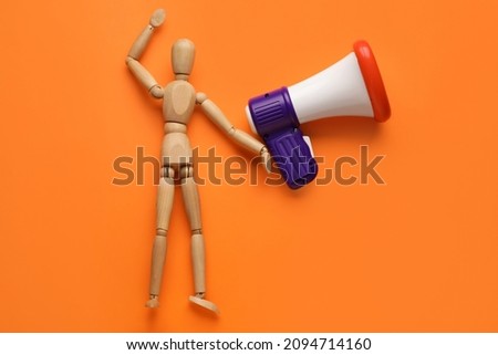Wooden mannequin with toy megaphone on color background